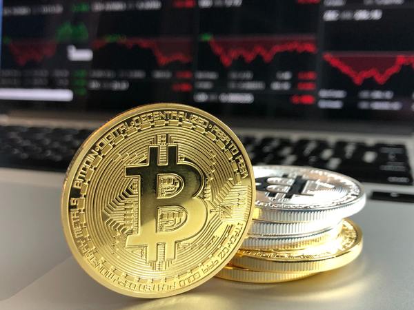 Gold and silver bitcoin coins with charts and graphs.