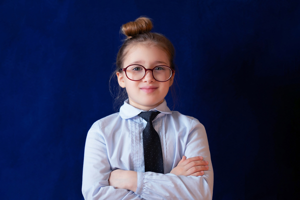 Girl standing with her hands crossed wearing glasses.