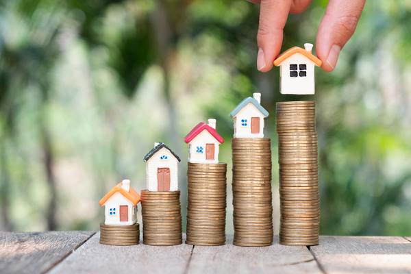 Stacks of coins with miniature houses on top.