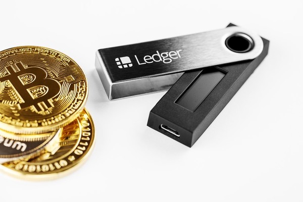 Gold coins with the bitcoin symbol and Ledger hardware wallet.