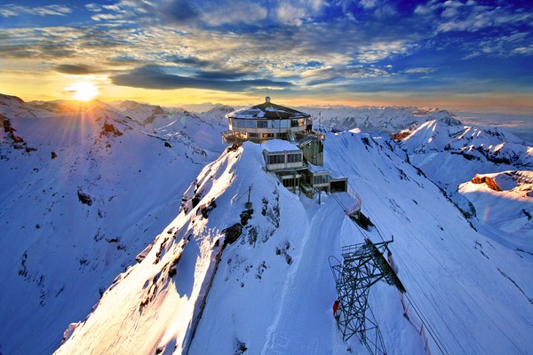 Circular building on top of a snow covered mountain.